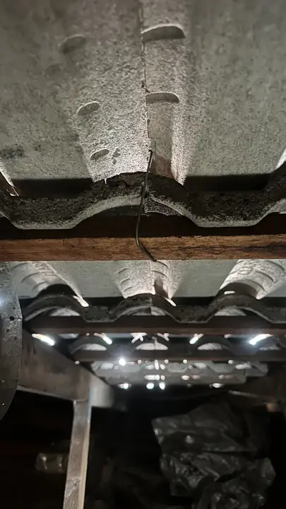 Suspected asbestos cement sheeting under the tiles, seen from the roof space.