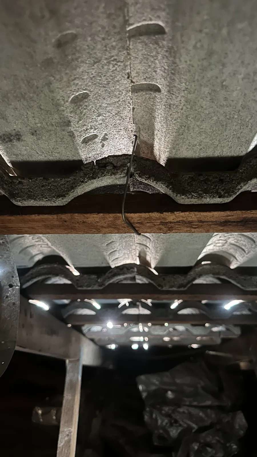 Suspected asbestos cement sheeting under the tiles, seen from the roof space.